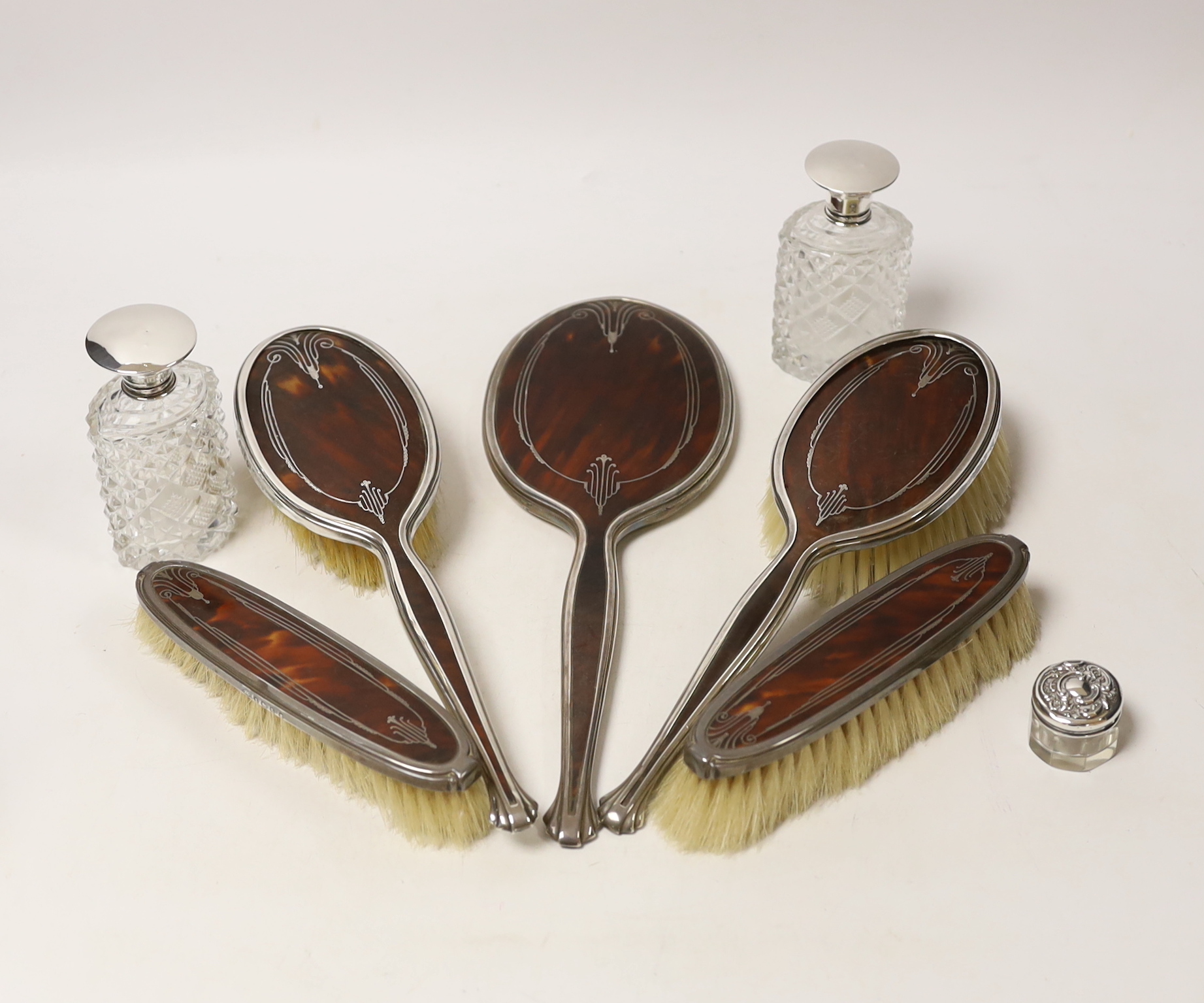 A George V silver and tortoiseshell pique mounted dressing table set, Adie Bros, Birmingham, 1934, and three silver topped toilet jars.